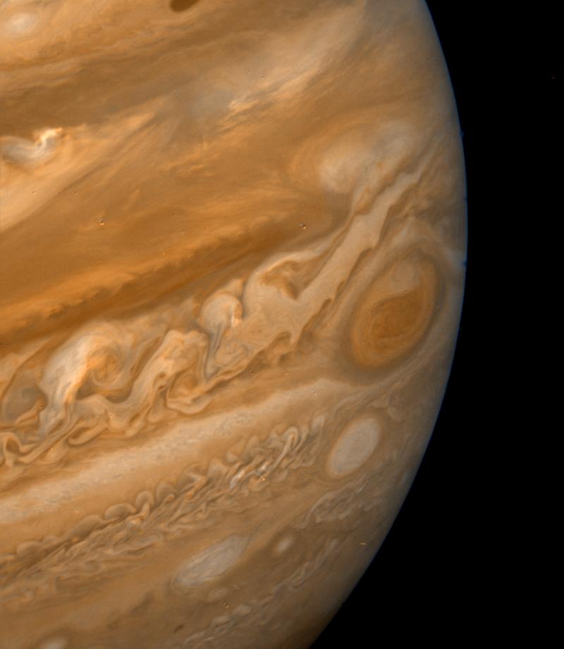 Against a black background, an enormous sphere in various shades of orange fills most of the frame and extends beyond the picture, to the left, top...